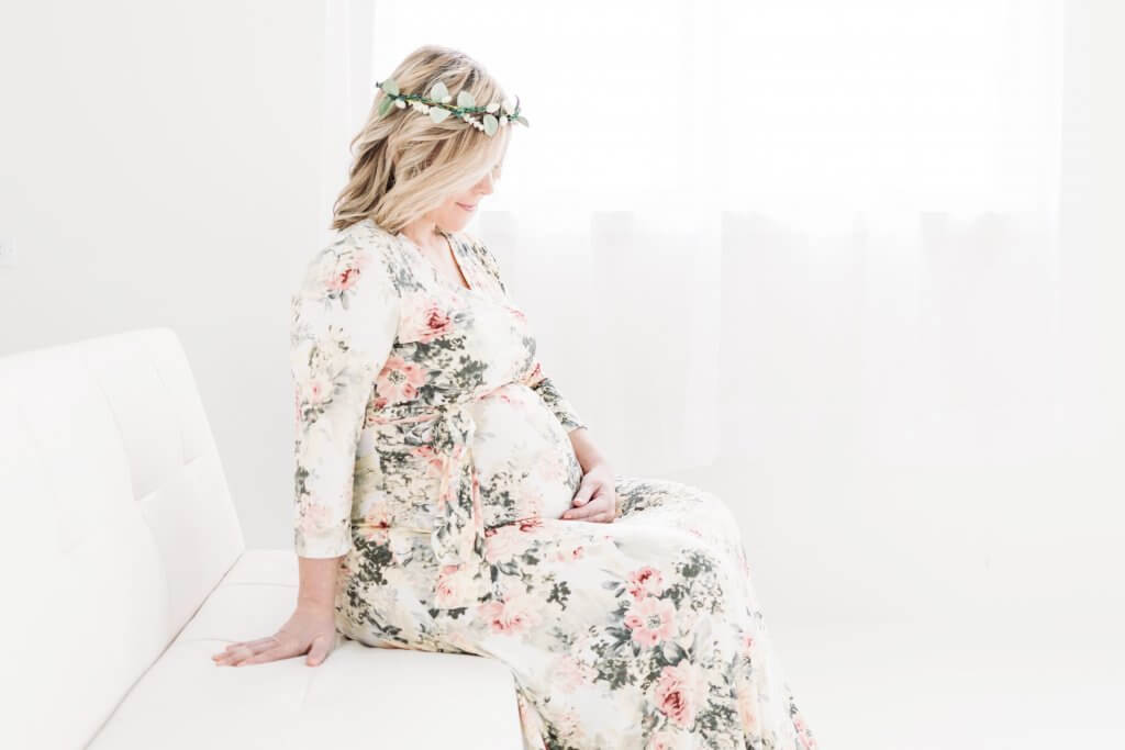 A pregnant woman in a floral dress and floral crown for maternity photos