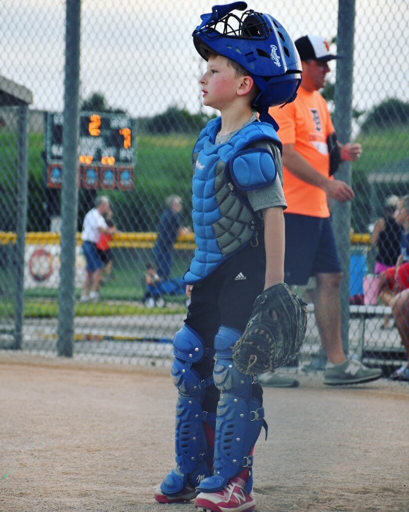 A boy playing catcher in a game of baseball.
