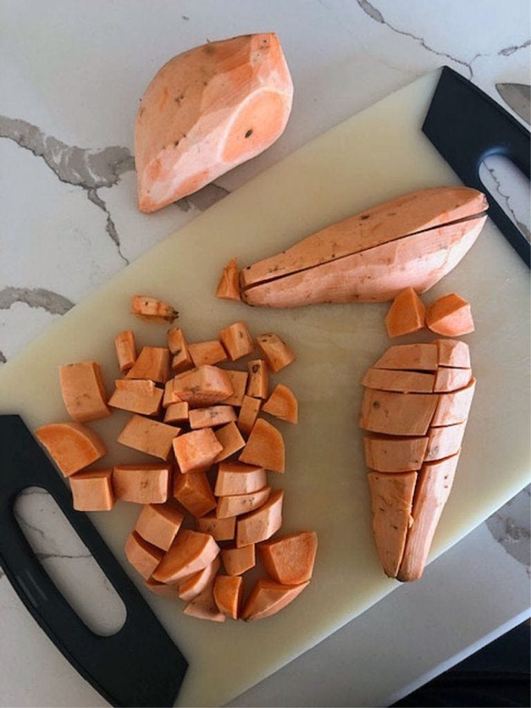 raw sweet potatoes diced on a cutting board
