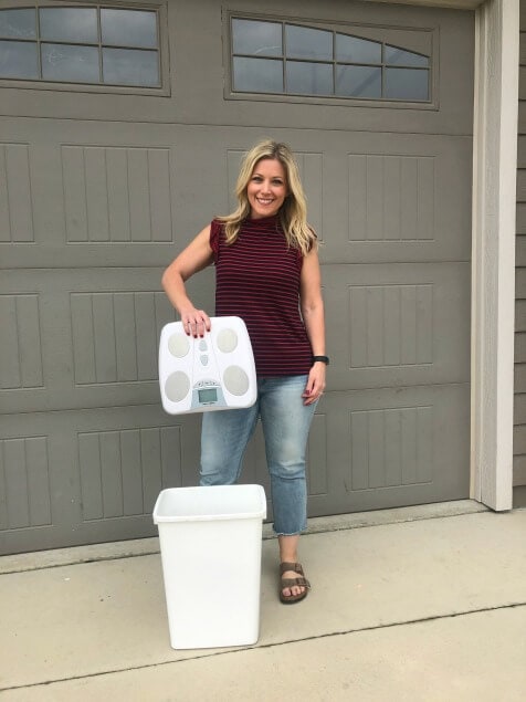 A woman holding a scale over a trash can