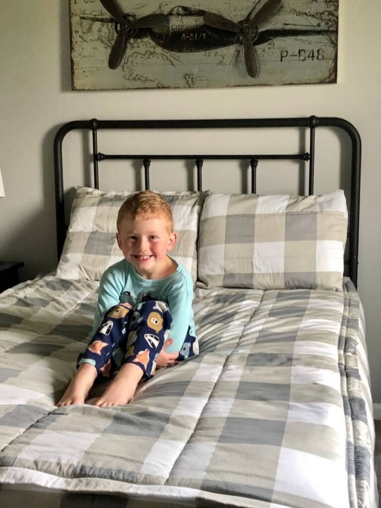 a young boy smiling on top of his bed