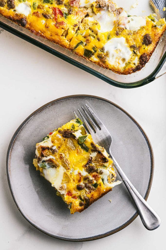 a plate of breakfast casserole on a plate with a fork and the a 9x13 dish filled with breakfast casserole