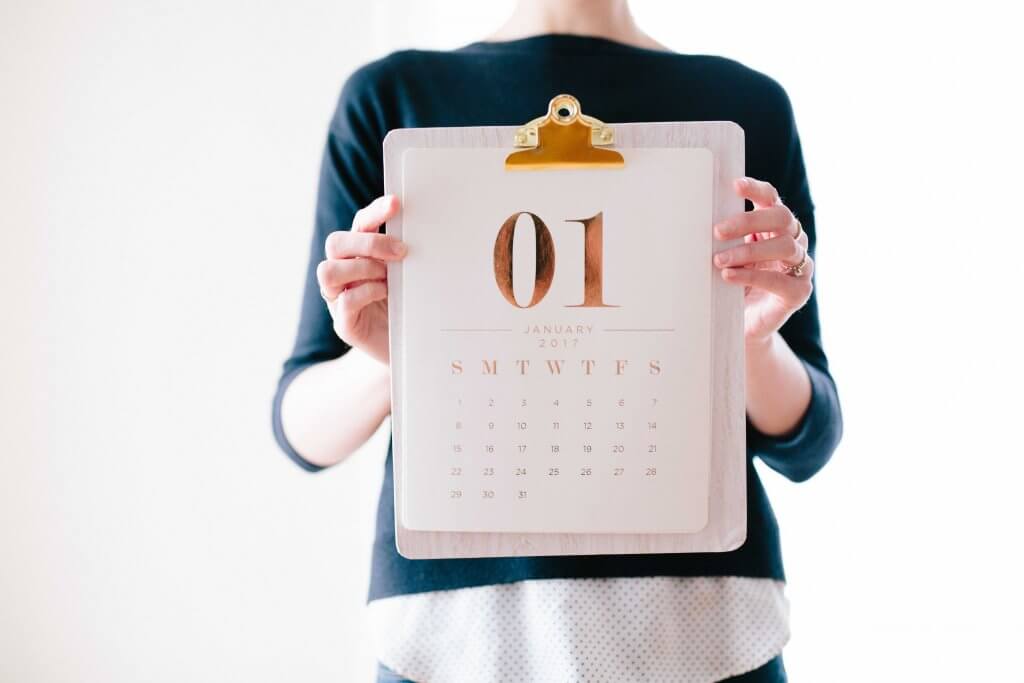A woman holding a calendar with January 1st on it