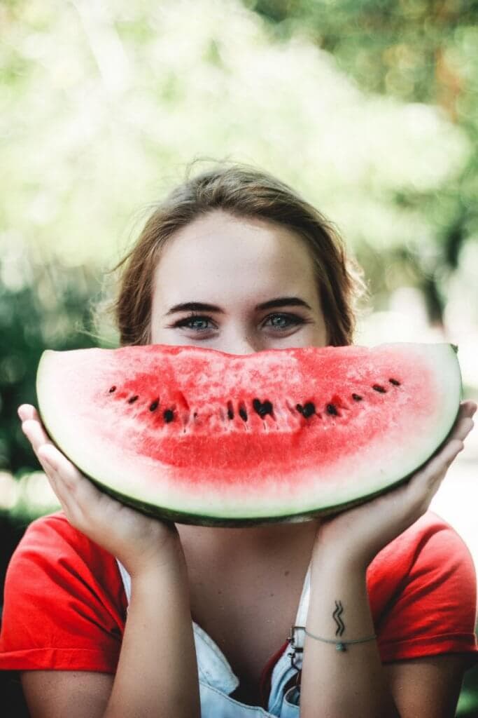 A woman with a watermelon in front of her face