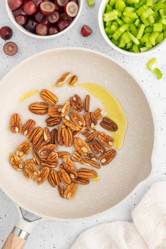 pecans in a white skillet with oil