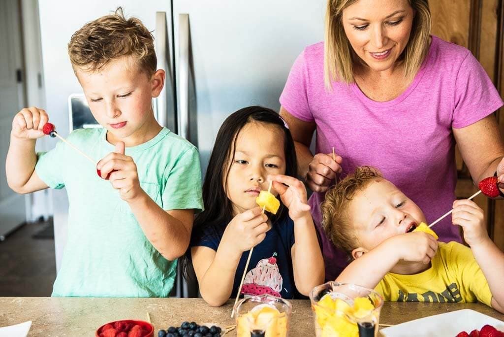 Adult and three children making fruit kabobs