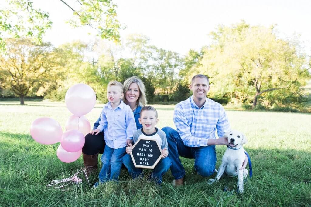 A family of four and their labrador announcing they are having a girl.