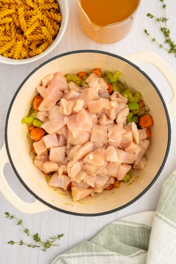 raw chicken in a dutch oven on top of diced veggies