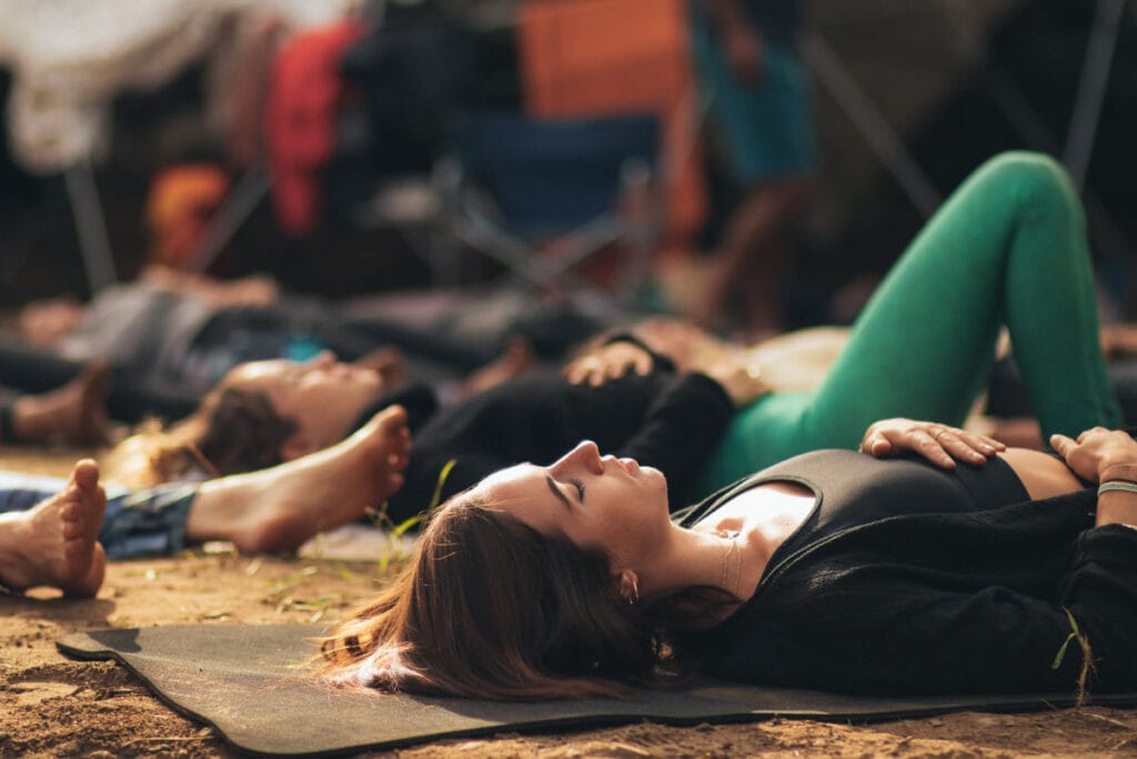 a group of women laying down with their hands on their heart and abdomen, meditating