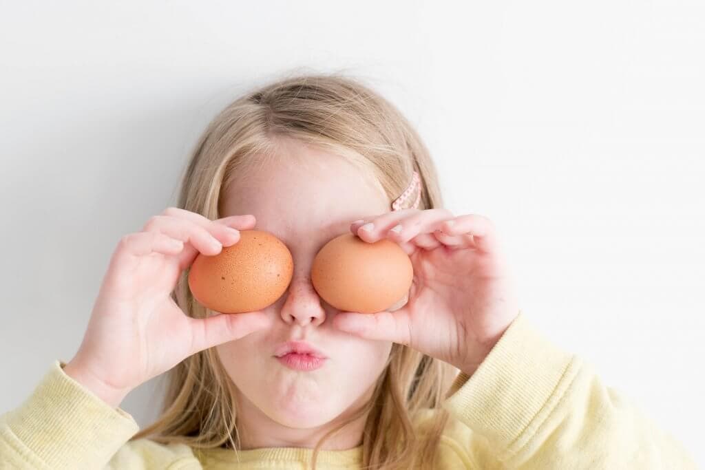 Little girl putting eggs over her eyes