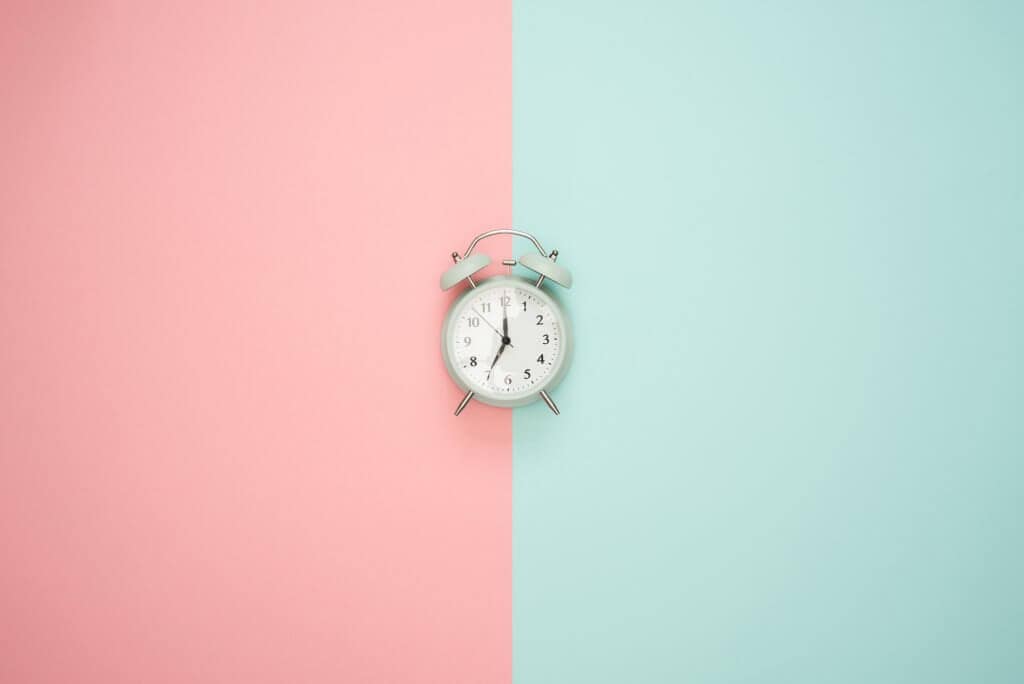 A clock with a pink and blue background