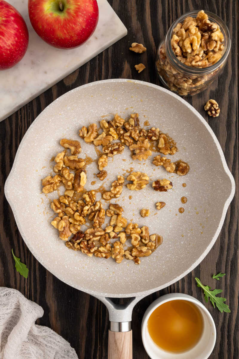 walnuts in a white pan being toasted