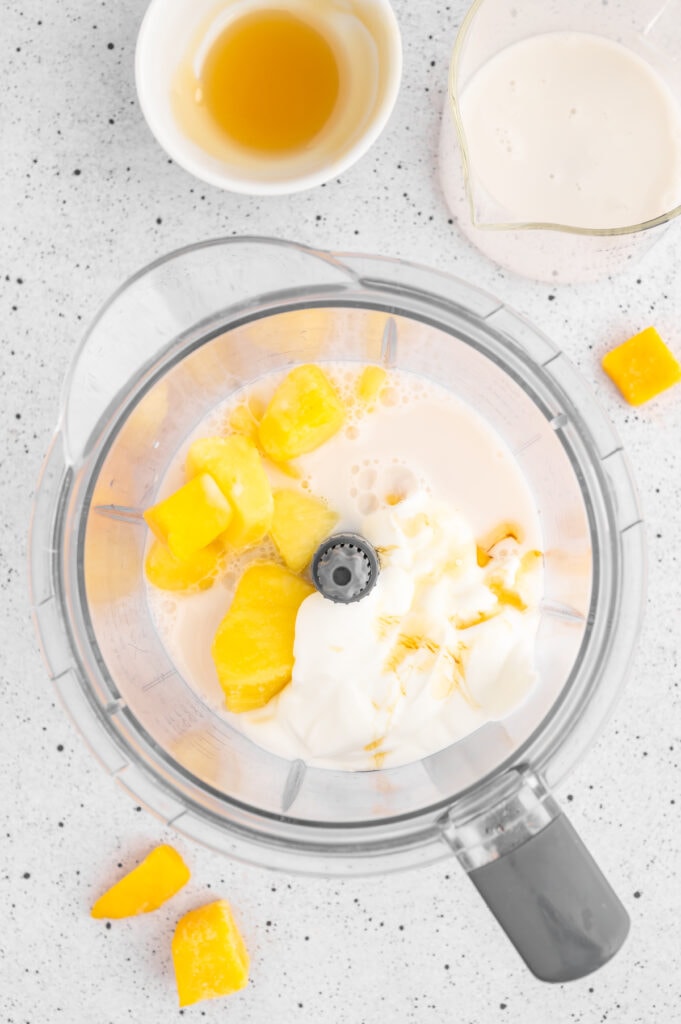 Ingredients for mango pineapple smoothie in a blender before it is blended