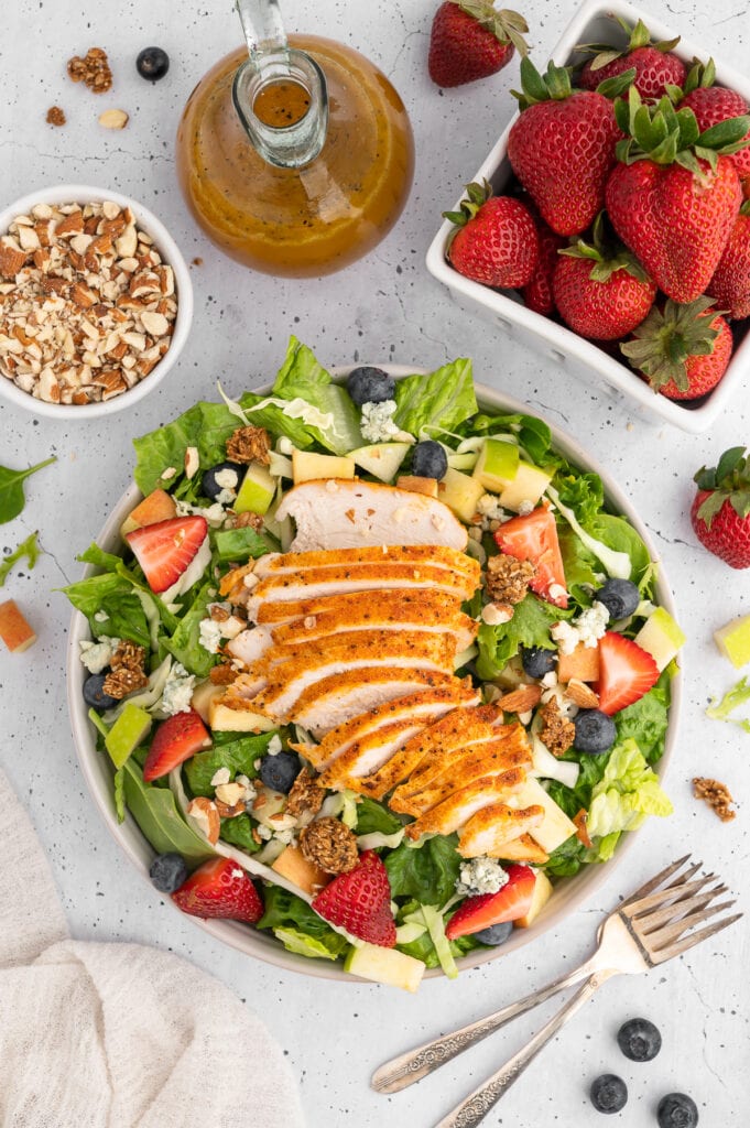 overhead picture of market salad with the dressing, strawberries and nuts
