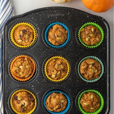 Healthy Pumpkin muffins in a black muffin tin with muffins and a napkin