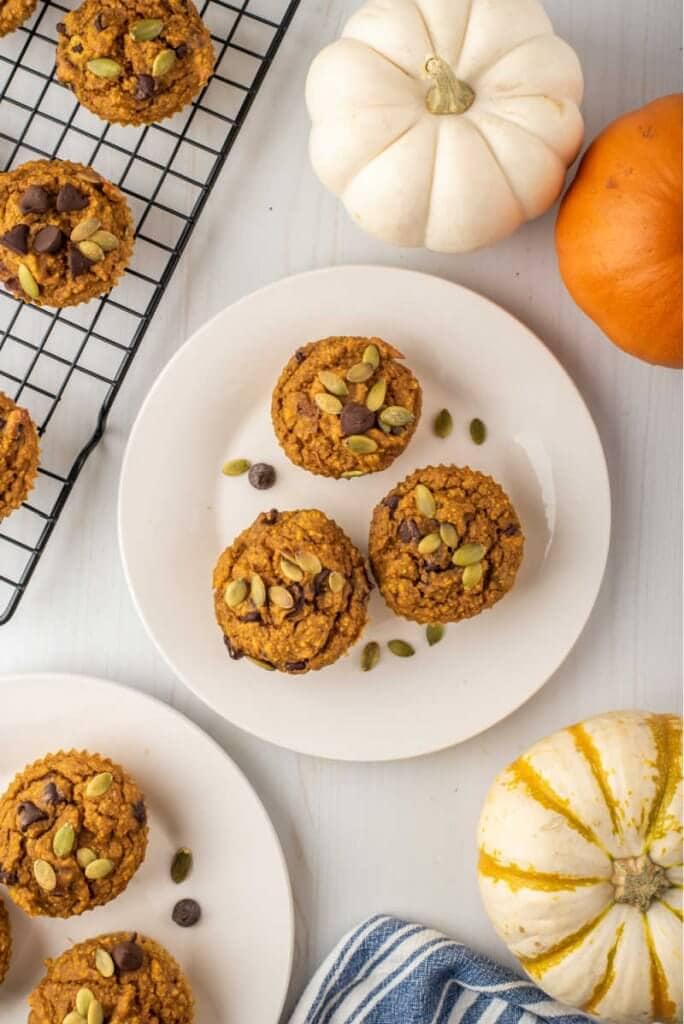 plated healthy pumpkin muffins on white plates with pumpkins and a napkin
