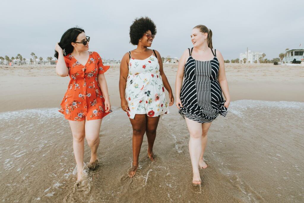 Three women walking along the beach and smiling