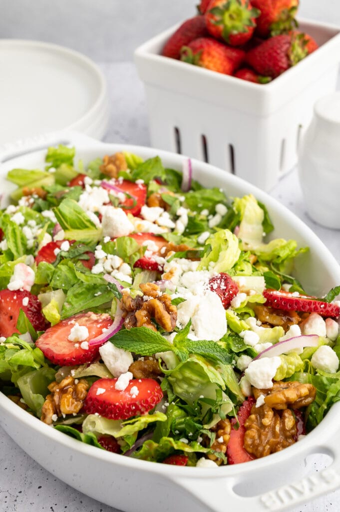 Up close picture of strawberry goat cheese salad with a bowl of strawberries behind the bowl