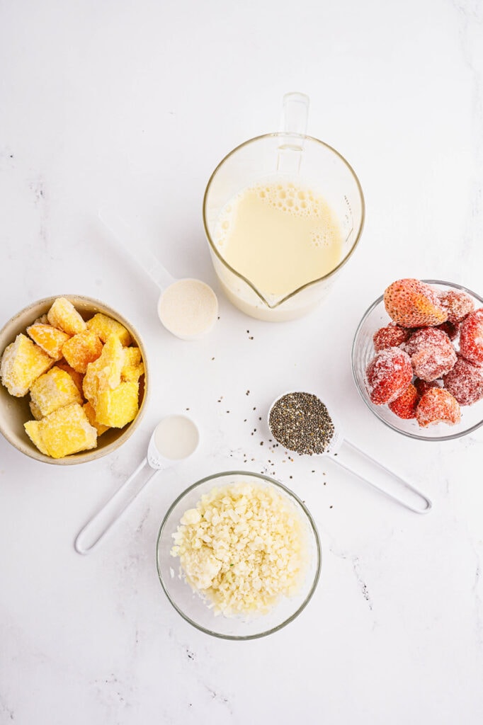 ingredients for strawberry mango smoothie in measuring cups