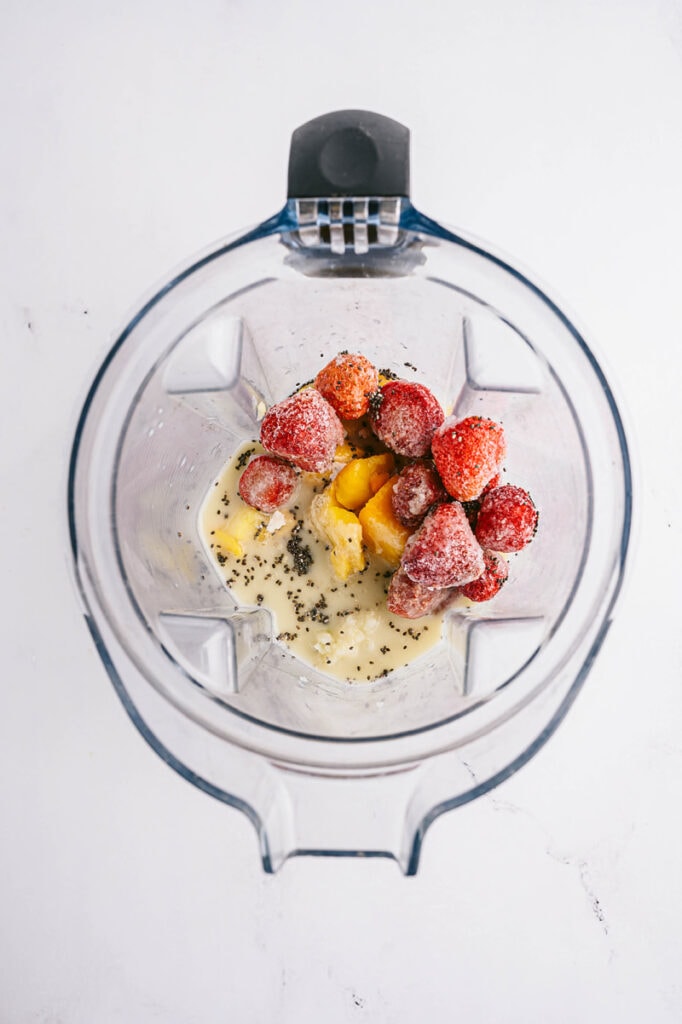 ingredients for strawberry mango smoothie in a blender with the photo from the top