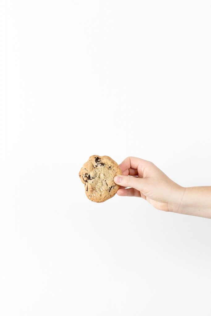 A white background and a person holding one cookie