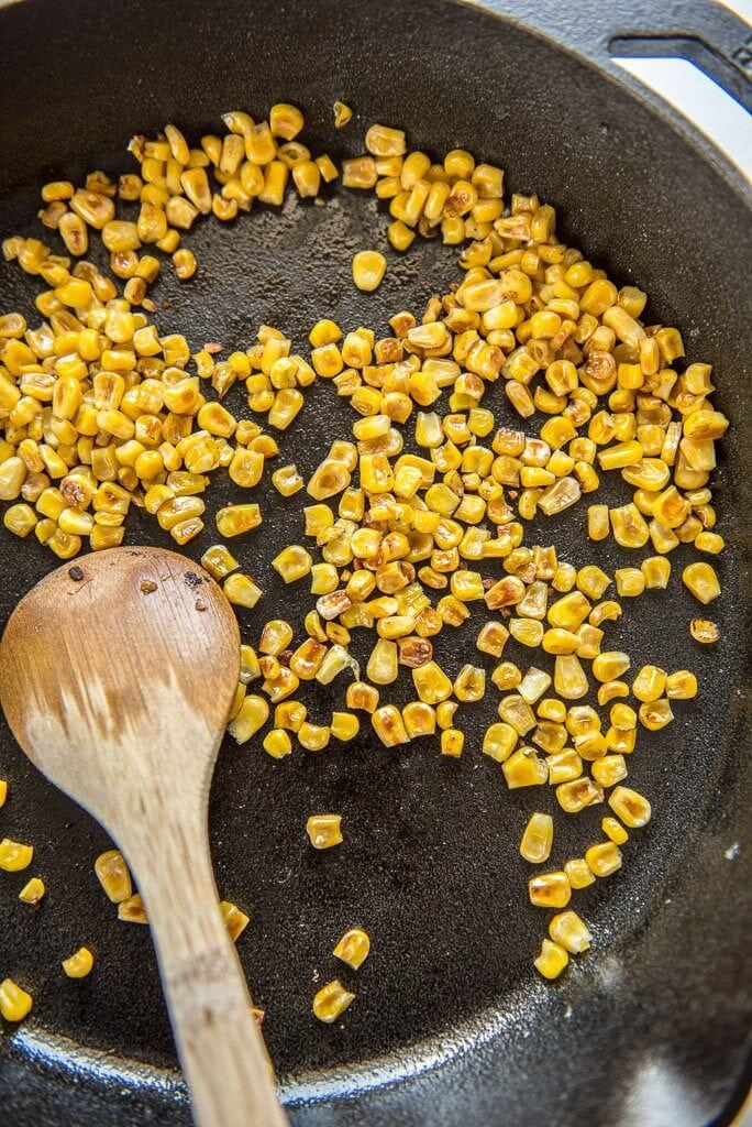 Skillet with corn and wooden spoon for turkey taco bowls with cauliflower rice