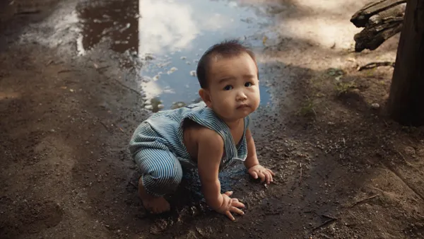 a baby plays in the mud