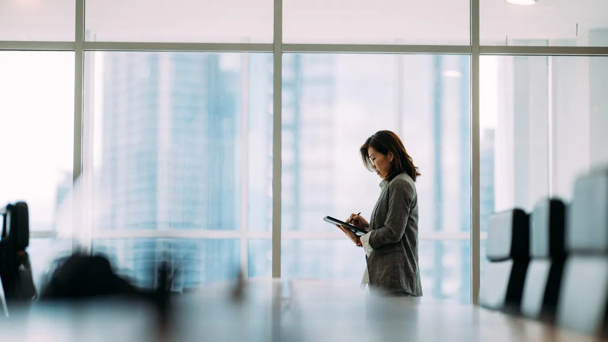 an executive reviews information on their tablet inside a boardroom