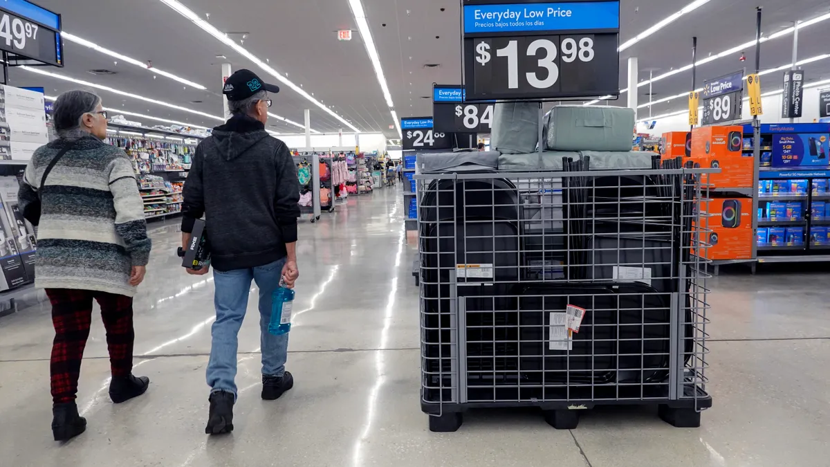 Two people walk down a store aisle past a sign that reads, "Everyday Low Price."