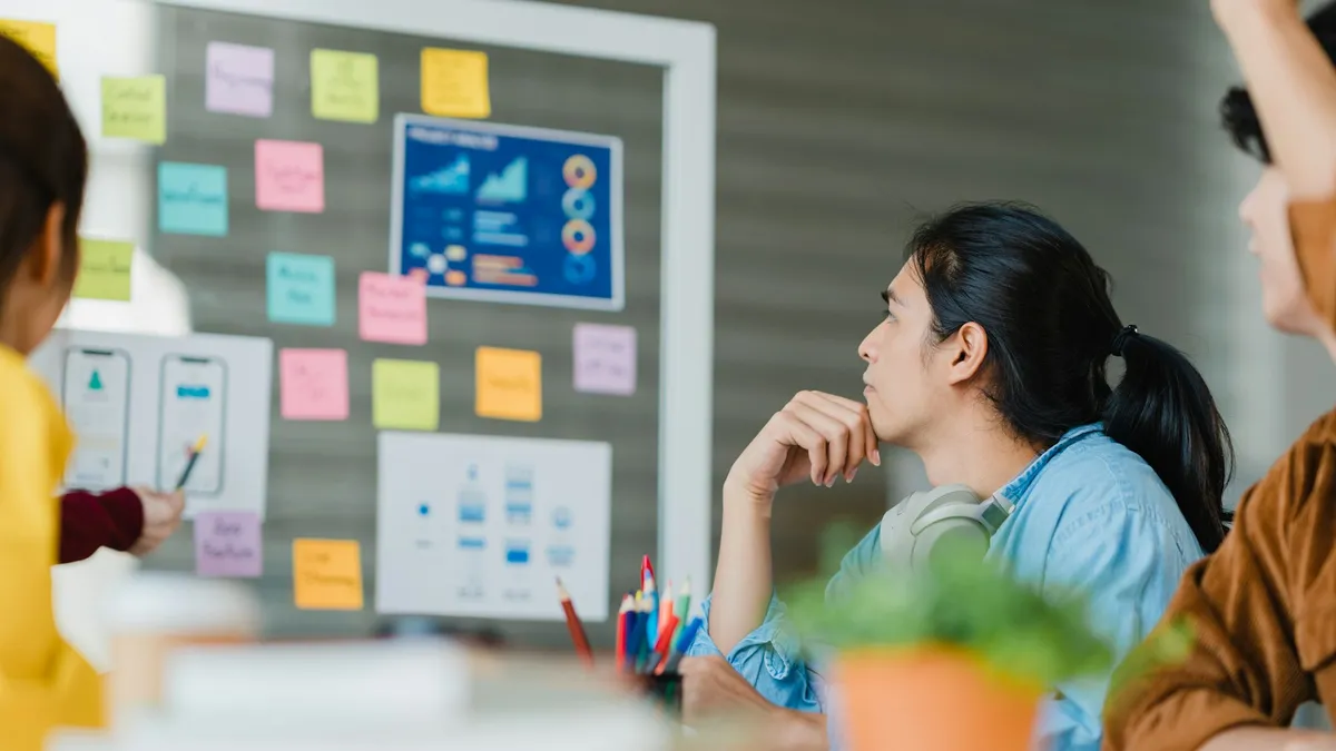 Person sitting in front of whiteboard filled with sticky notes