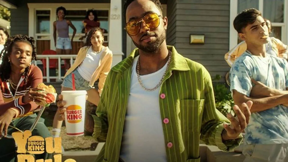 A group of young people eat Burger King in front of a grey house.