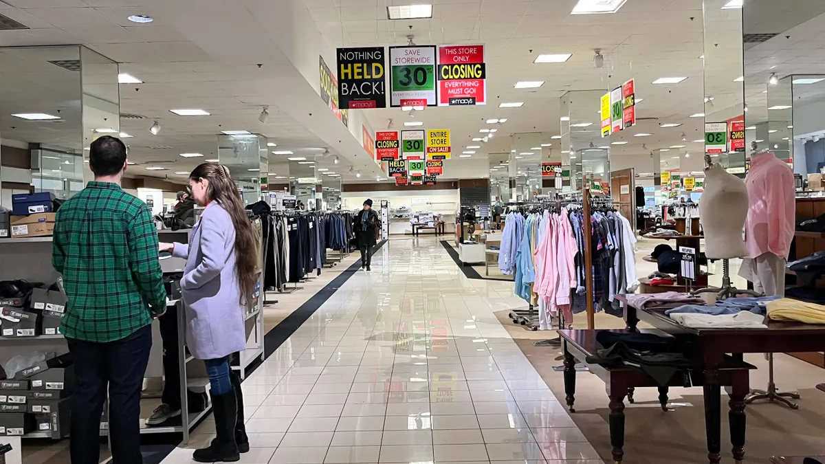 Shoppers look through a store closing sale at Macy's.