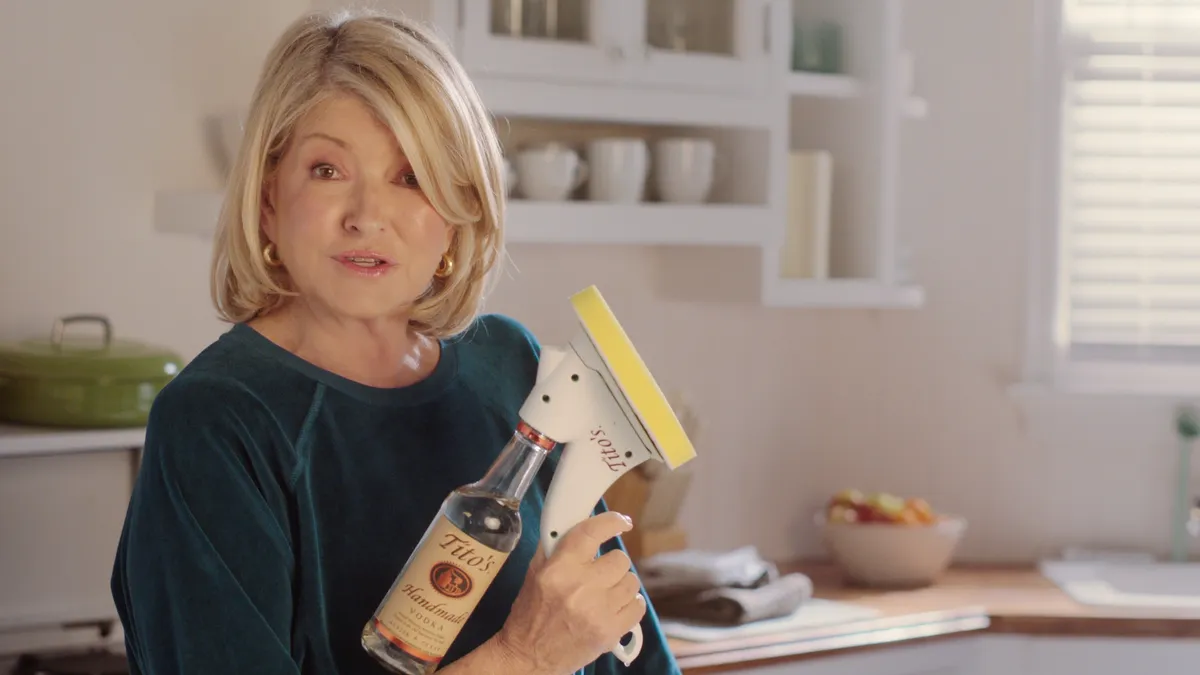 Martha Stewart holds a bottle of Tito's vodka with a special cleaning attachment