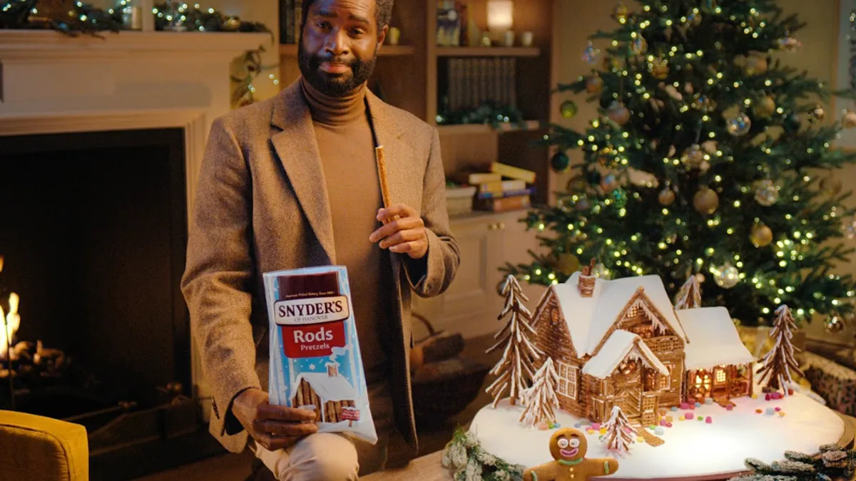 A spokesperson with a gingerbread person and a Snyder's pretzel cabin